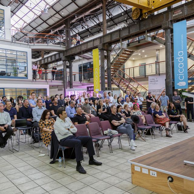 A seated audience in a large industrial hall during a Spark Festival talk