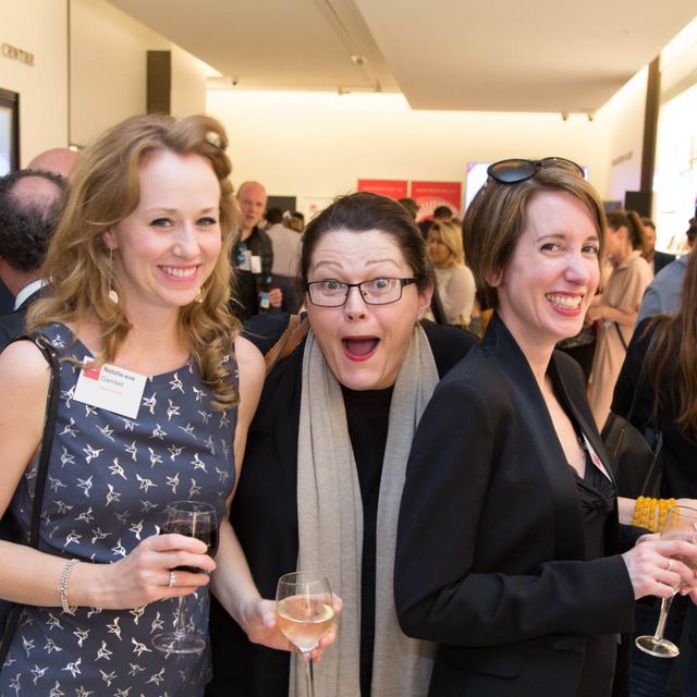 Three women laughing together with drinks at a Spark Festival networking event