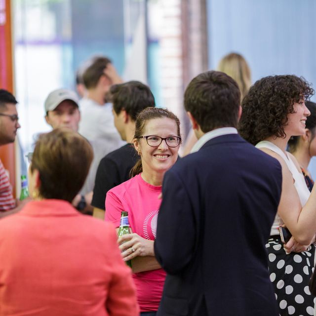 Attendees talking in a crowd, one wearing a pink Spark Festival t-shirt