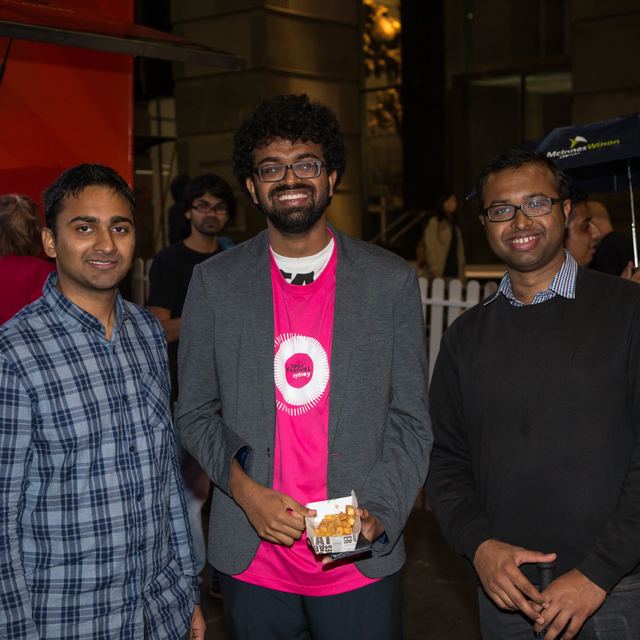 Three attendees at an evening event, one in a pink Spark Festival t-shirt