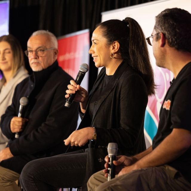 A panellist speaking into a microphone alongside three fellow panellists