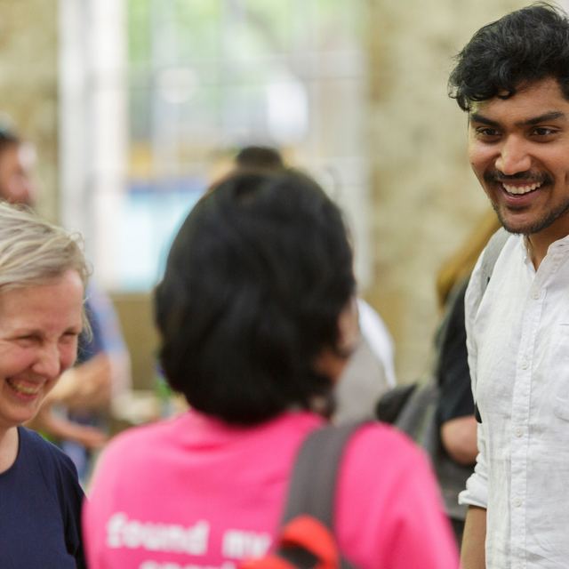 Attendees in conversation, one wearing a pink