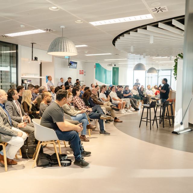 A seated audience filling a modern office space for a Spark Festival session